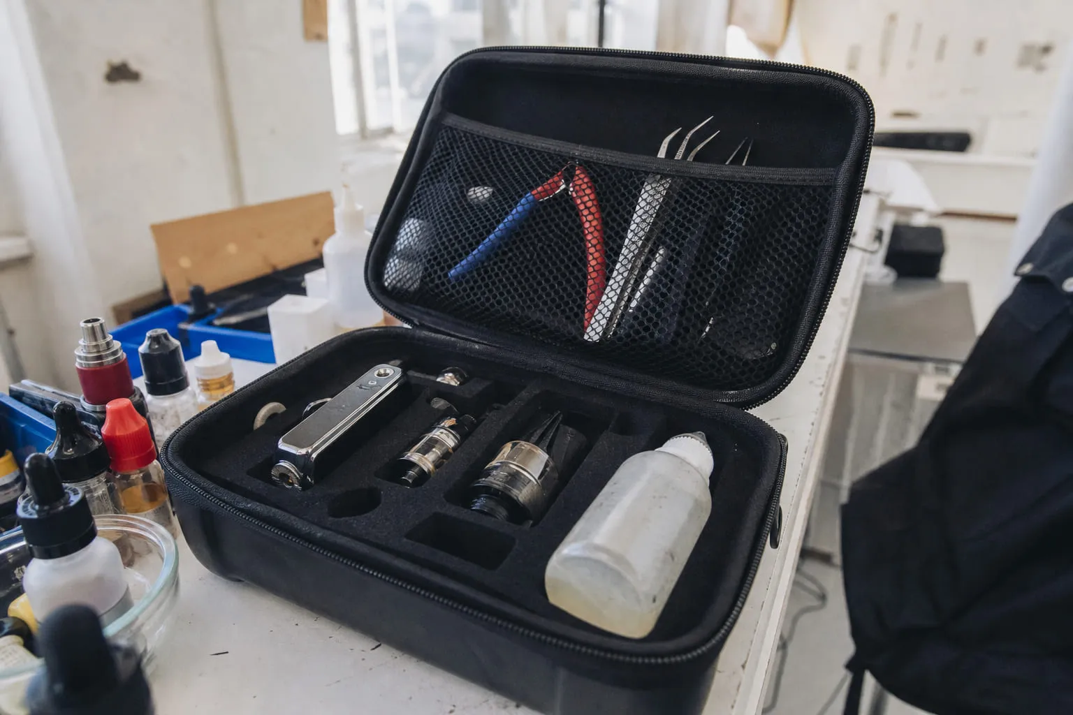 Un étui de transport ouvert contenant du matériel de vape, flacons et pinces
