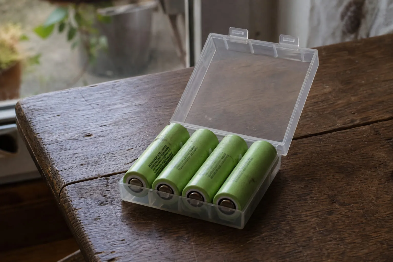 Accus cylindriques dans leur étui plastique de transport, posés sur une table