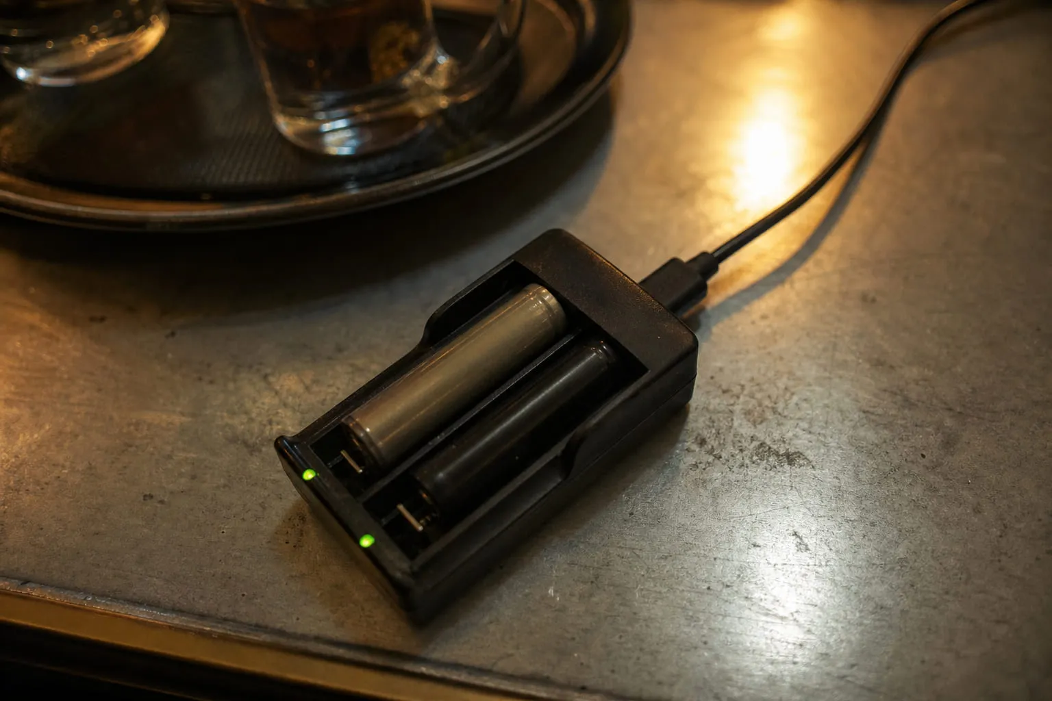 Un chargeur d'accus double slot en fonctionnement sur un bureau, câble USB