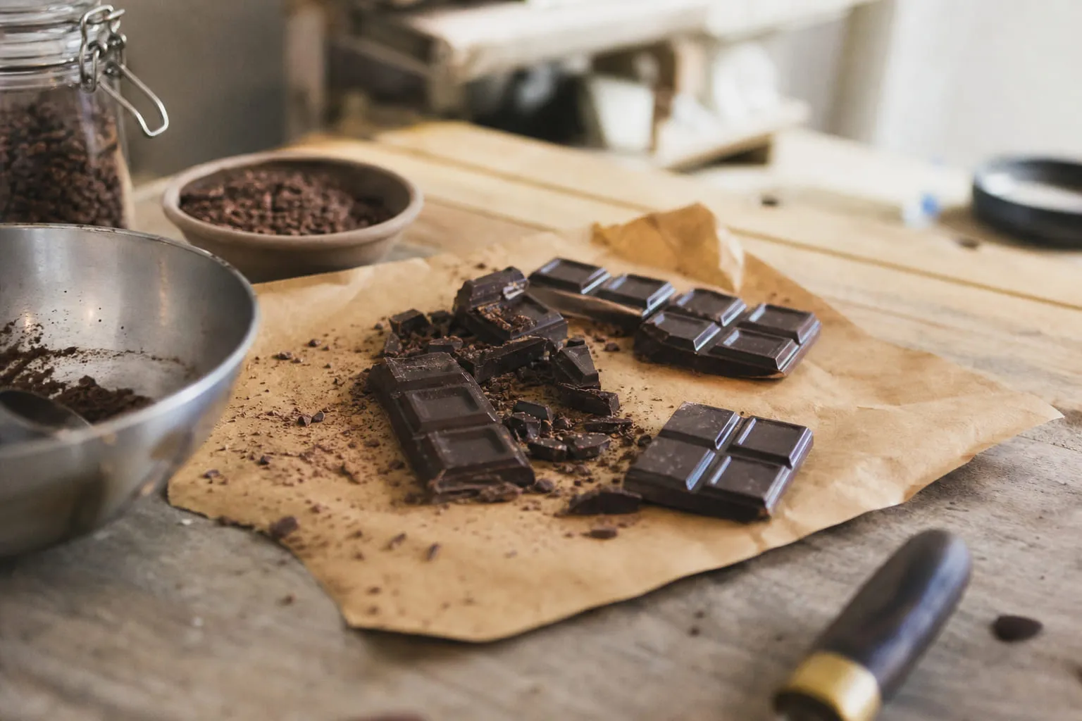 Une tablette de chocolat noir cassée en carrés sur du papier kraft