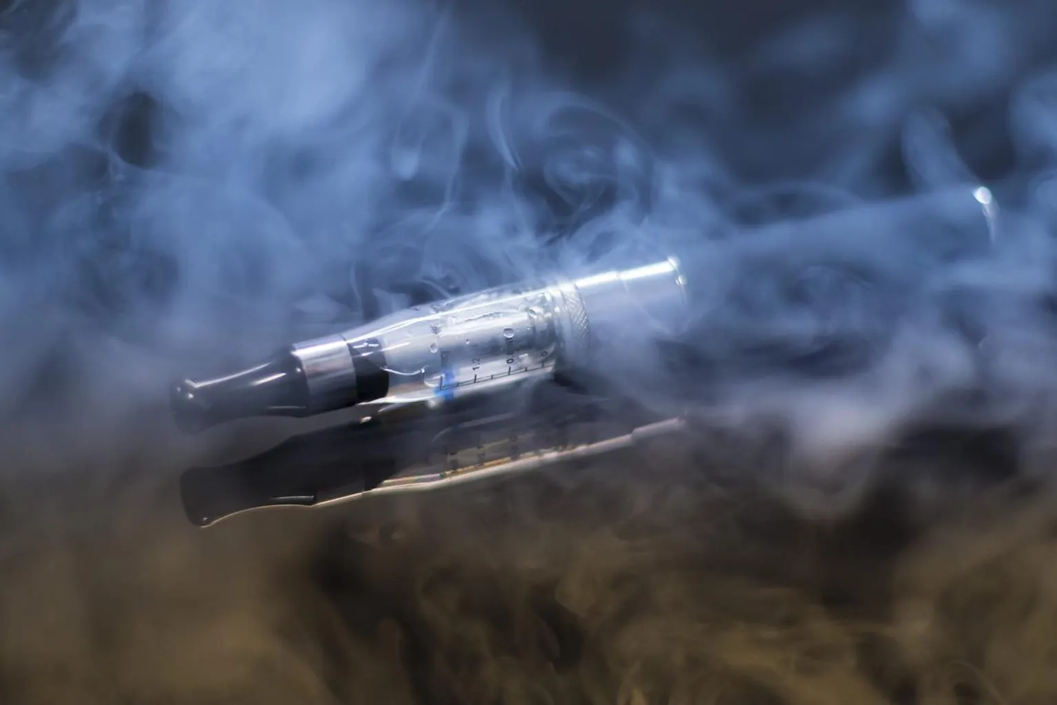 Homme tenant une cigarette électronique, assis près d'une fenêtre