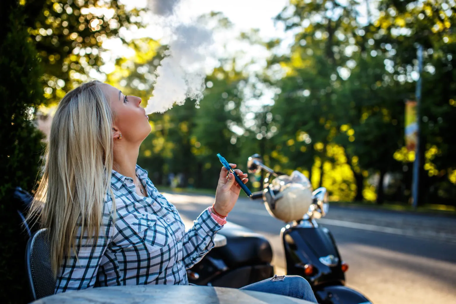 Une femme assise à une table, une cigarette électronique posée devant elle