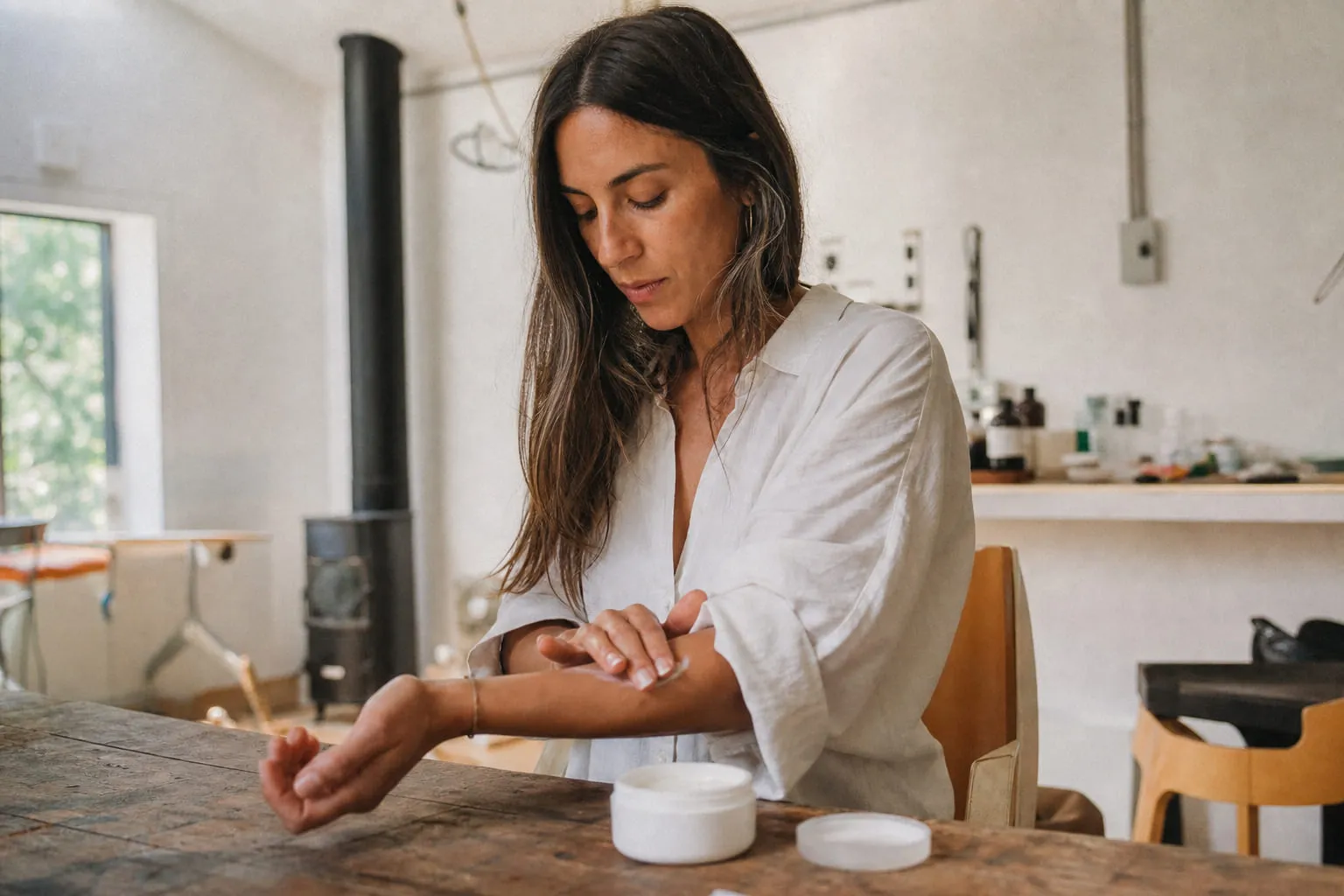 Un pot de crème cosmétique blanche ouvert, appliquée sur un avant-bras