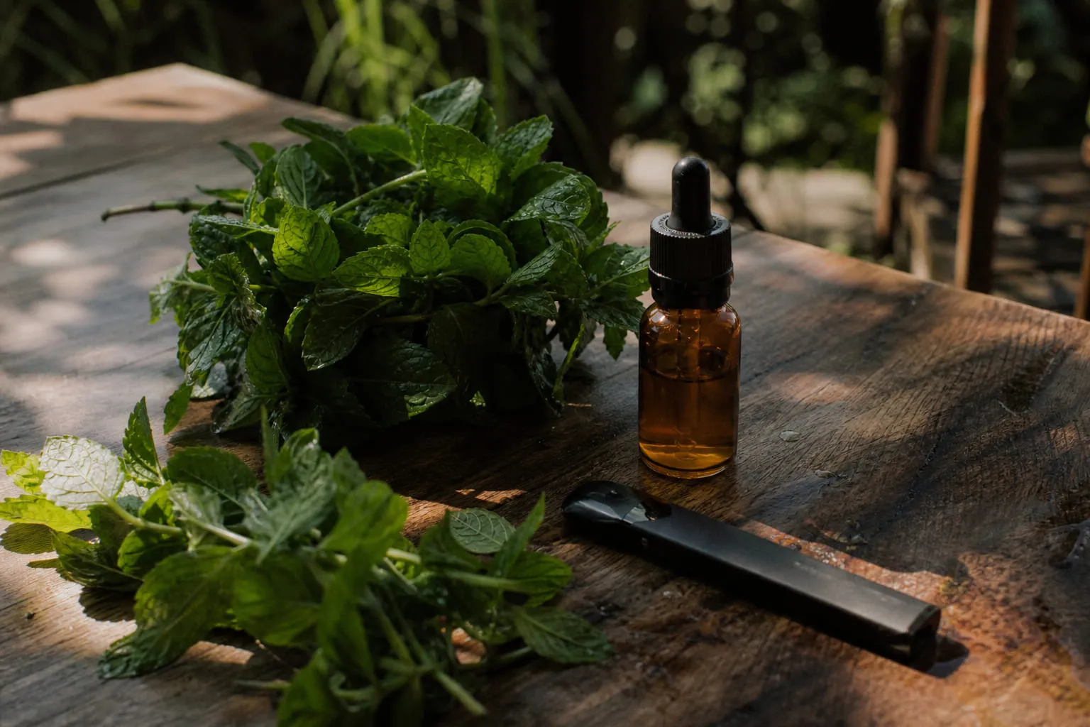 Bouquet de menthe fraîche à côté d'un flacon de e-liquide sur une table