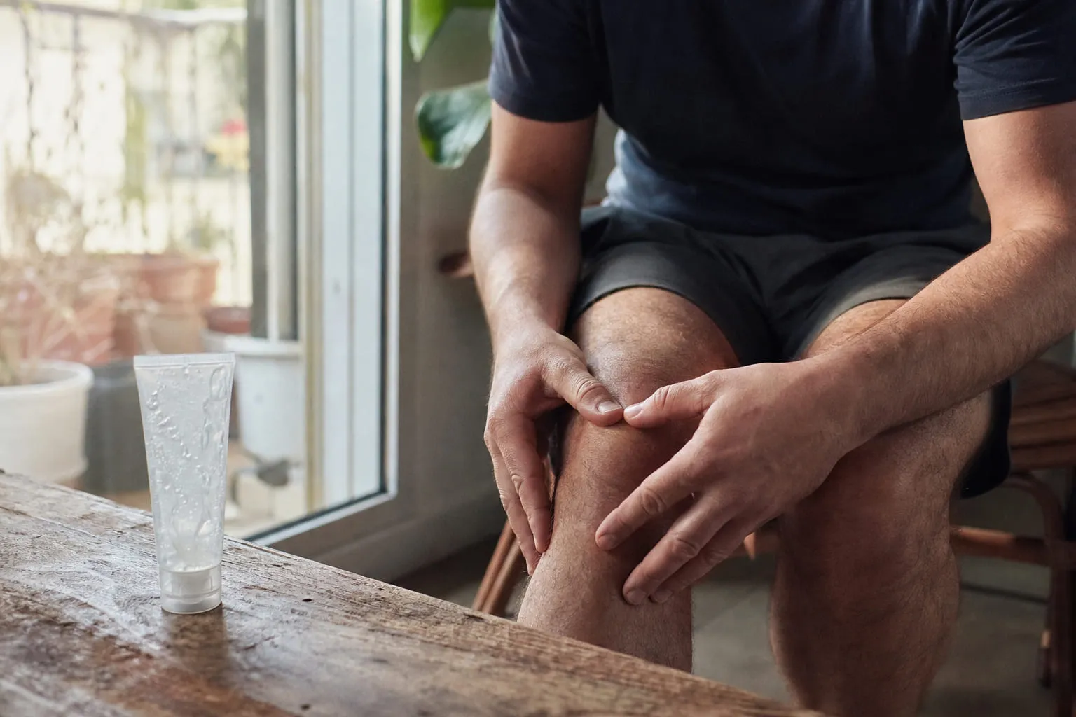 Un tube de gel transparent et un homme massant son genou après le sport