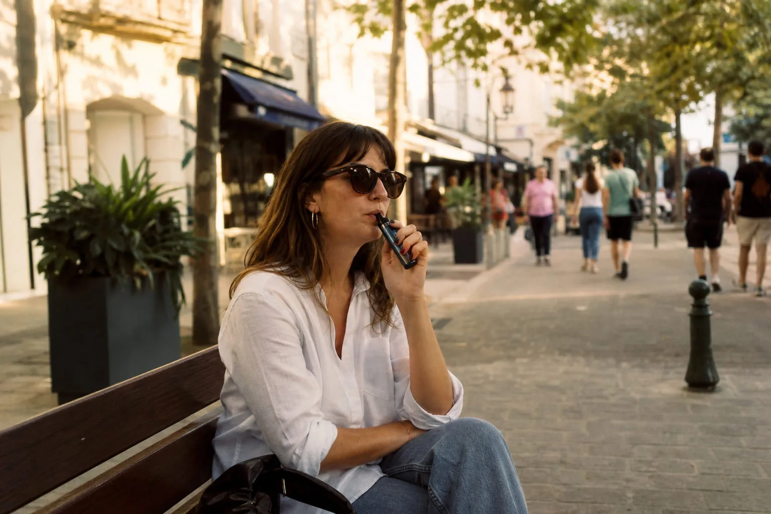 Femme vapotant sur un banc en plein air dans une rue piétonne