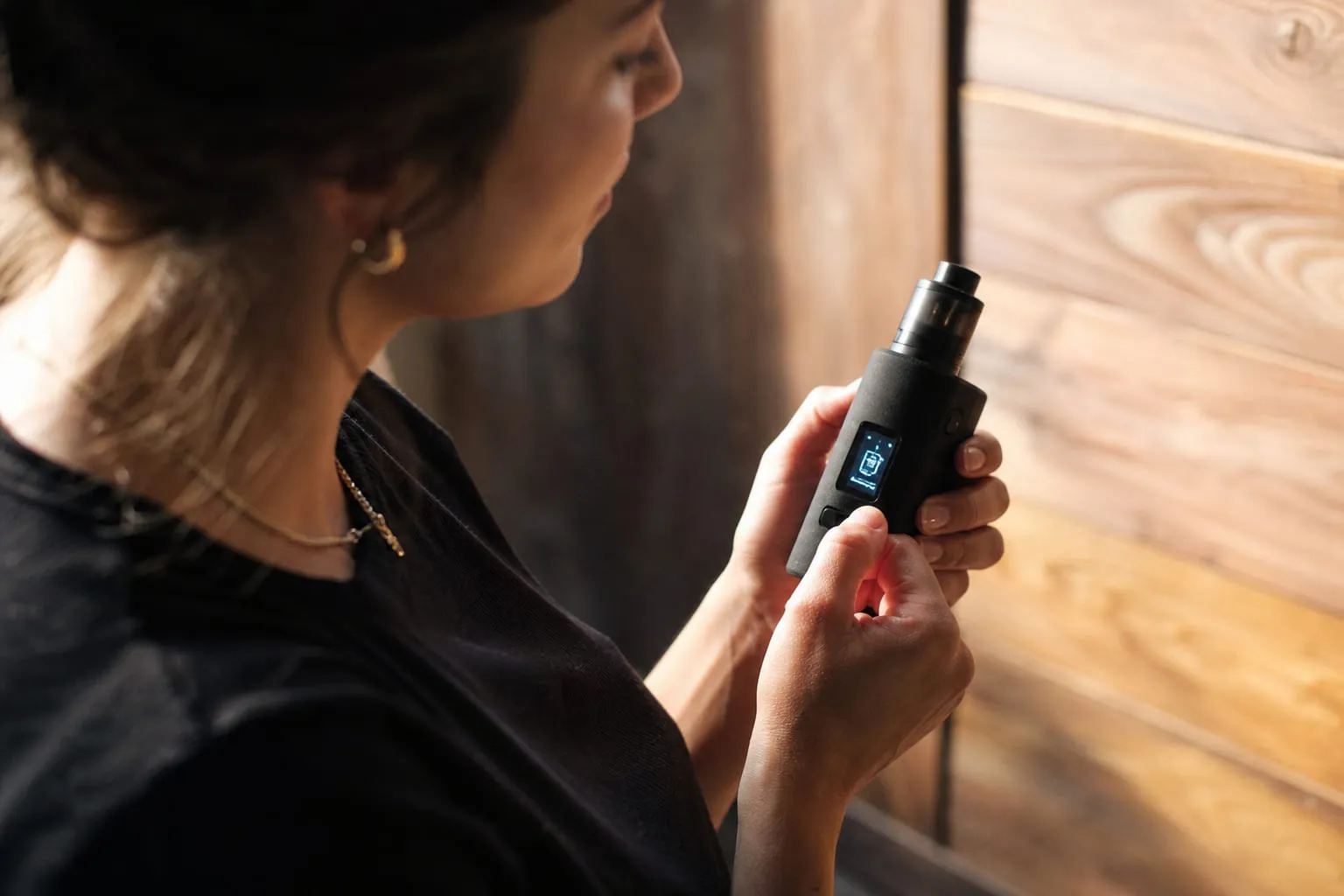 Box mod, atomiseur et flacon de e-liquide disposés sur un établi en bois