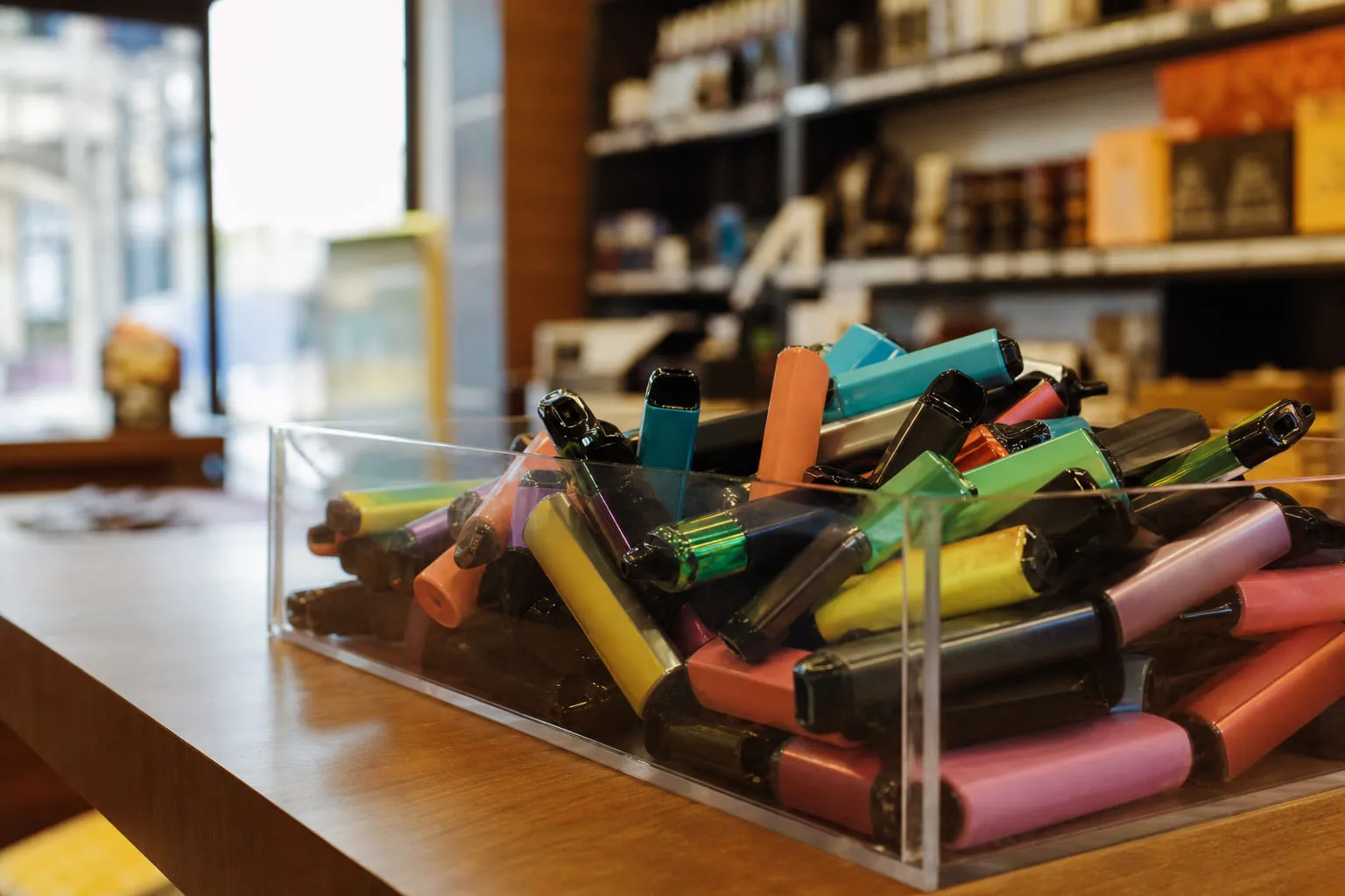 Petites cigarettes électroniques jetables colorées regroupées dans un bac de tri