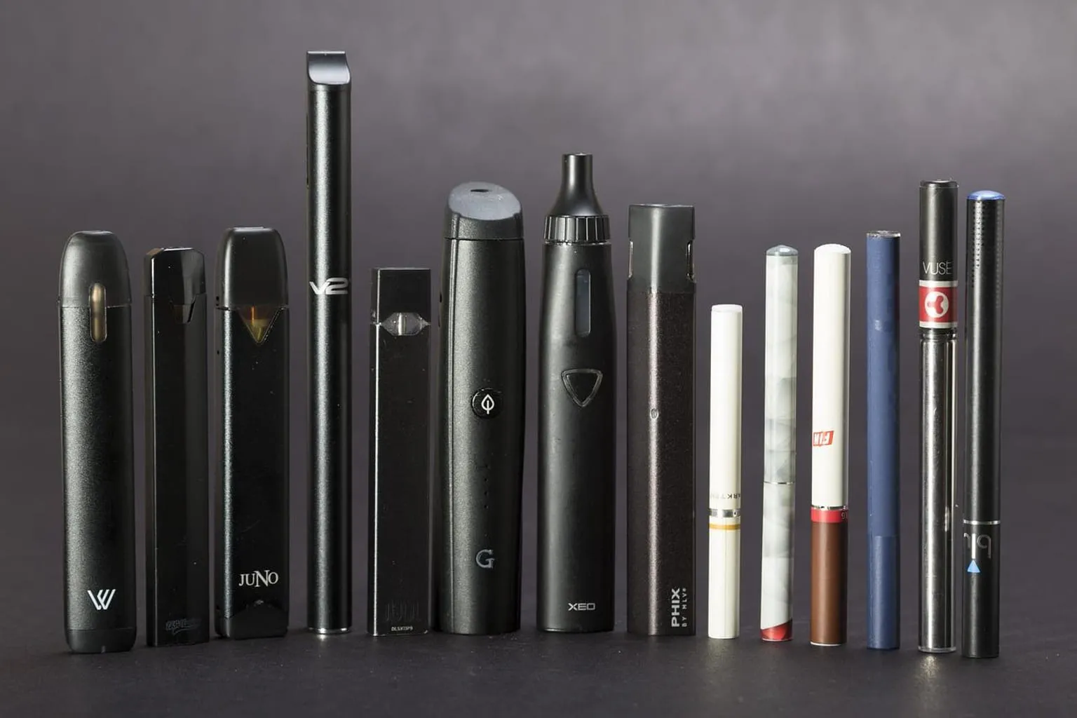 Plusieurs formats de cigarettes électroniques alignés sur une table en bois