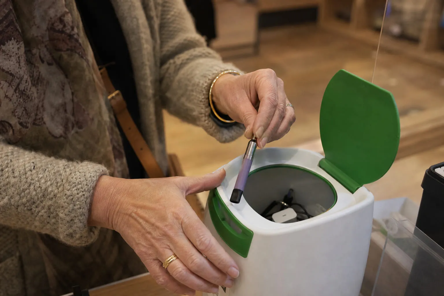 Mains déposant une vieille cigarette électronique dans un bac de collecte