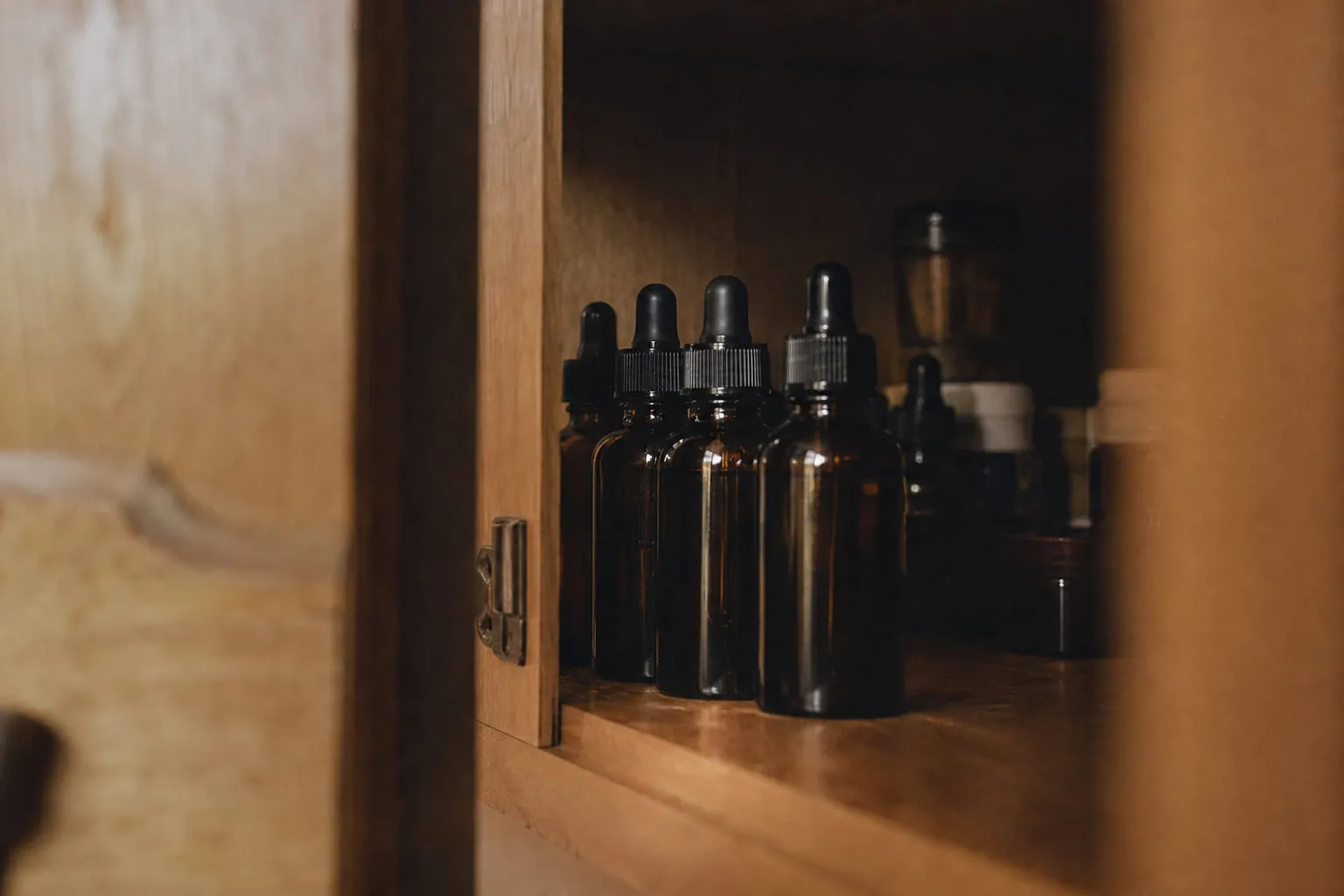 Flacons d'e-liquide en verre ambré alignés dans un placard entrouvert