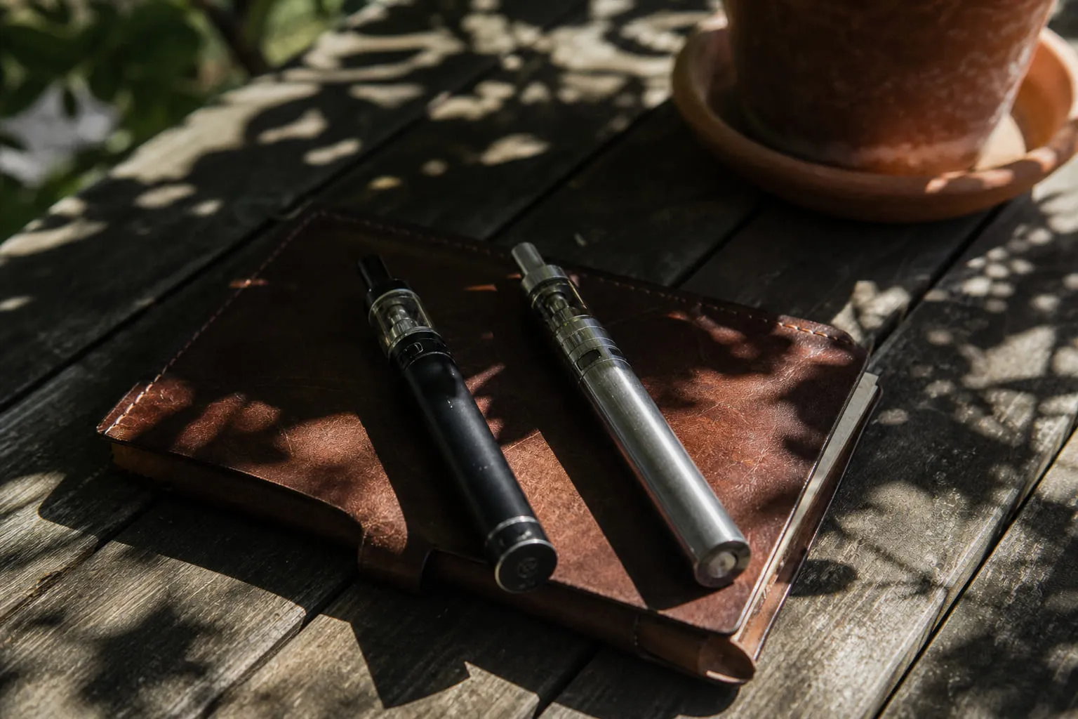 Deux cigarettes électroniques tubulaires posées sur un carnet en cuir