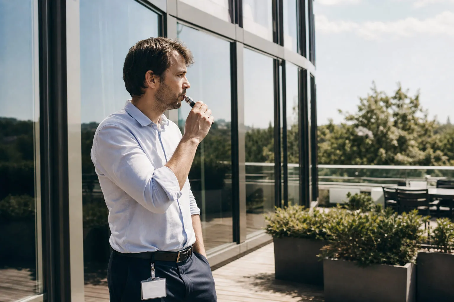 Salarié vapotant sur la terrasse extérieure d'un immeuble de bureaux